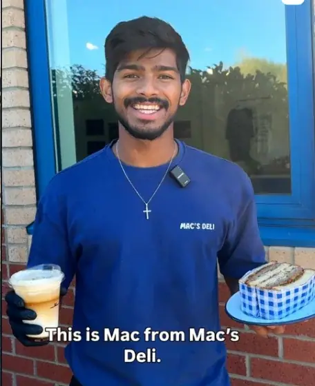 Mac from Mac’s Deli holding an iced coffee outside the shop